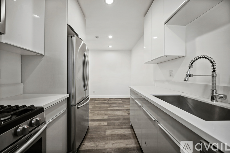 A modern kitchen with stainless steel appliances and a wooden floor.