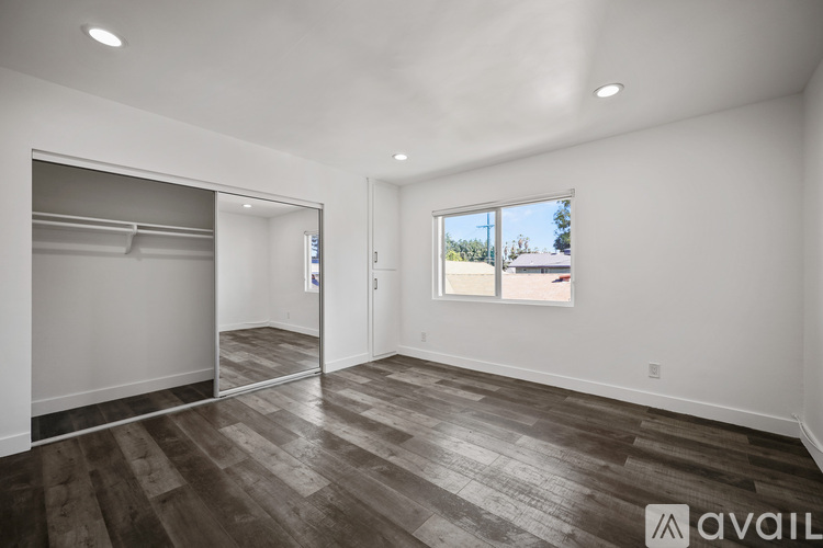A spacious room with wood flooring and a large window.