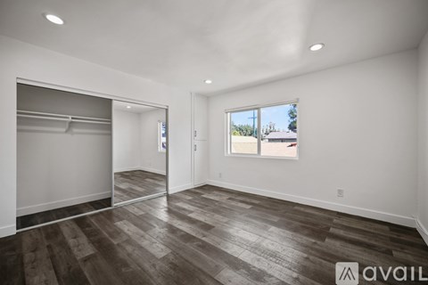 A spacious room with wood flooring and a large window.