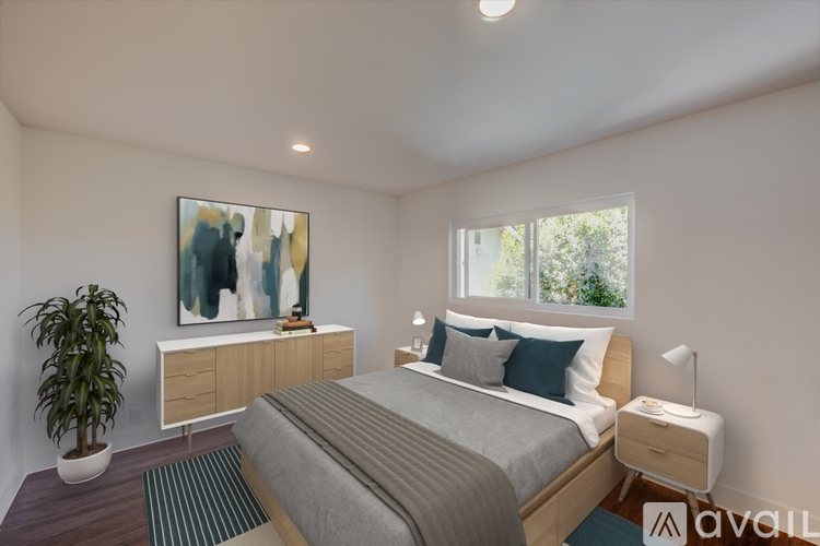 A bedroom with a bed, nightstand, and a painting on the wall.