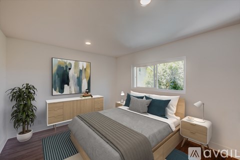 A bedroom with a bed, nightstand, and a painting on the wall.