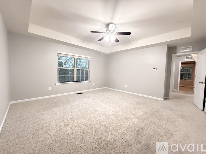 A spacious room with a carpeted floor and a ceiling fan.