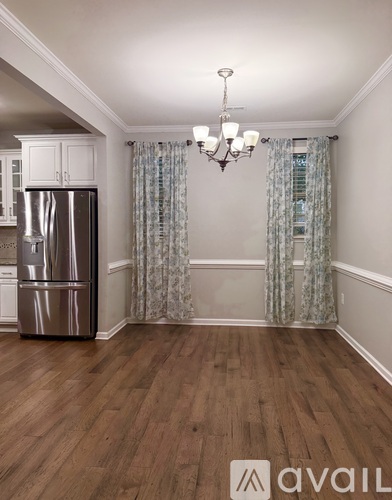 A kitchen with a stainless steel refrigerator and wooden flooring.