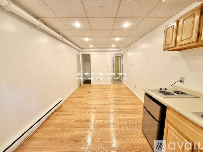A long, empty hallway with wooden floors and white walls.