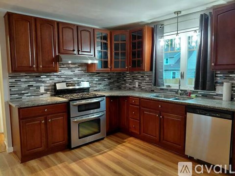 A kitchen with wooden cabinets and a stainless steel dishwasher.