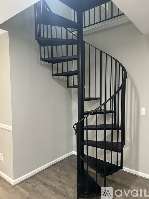 A spiral staircase with black railings and steps.