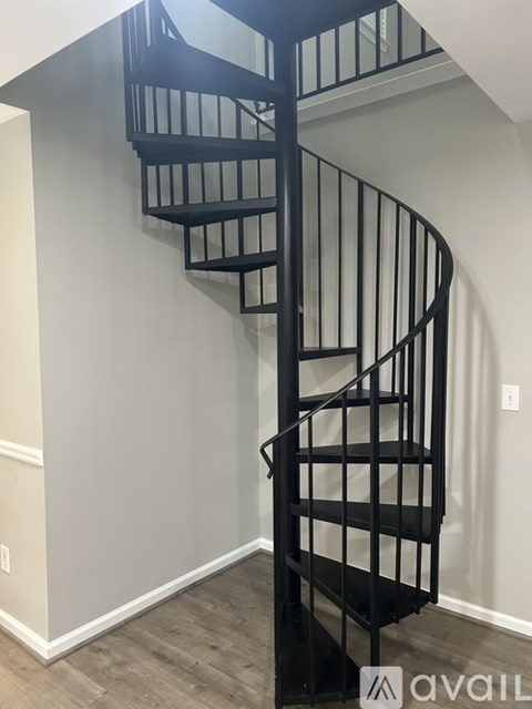 A spiral staircase with black railings and steps.