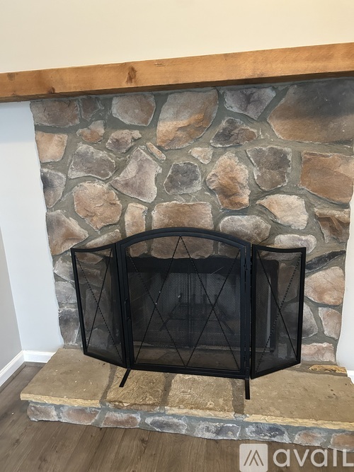 A black fireplace screen is mounted on a stone fireplace.