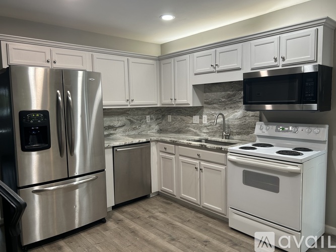 A kitchen with stainless steel appliances and white cabinets.