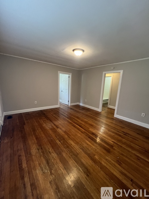A room with wooden flooring and two doors.