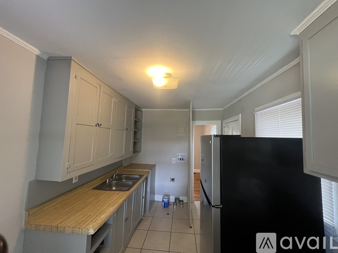 A kitchen with a black fridge and wooden countertops.