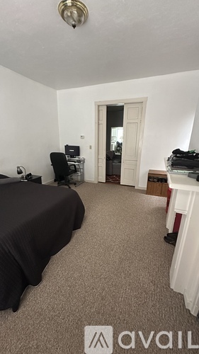 A bedroom with a bed, desk, and chair.