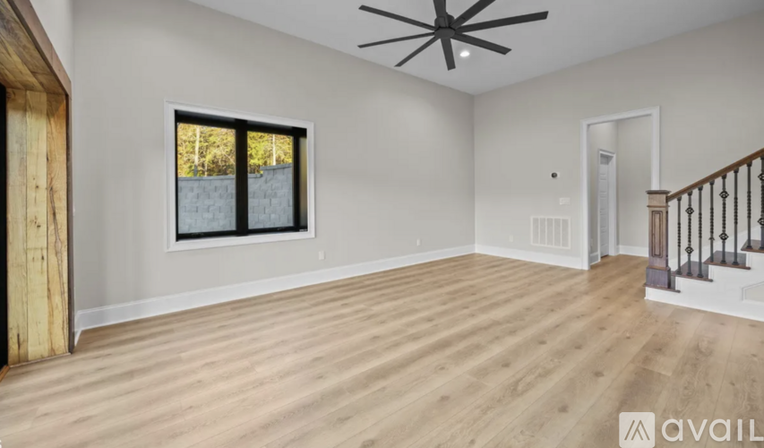 A spacious room with wooden flooring and a ceiling fan.