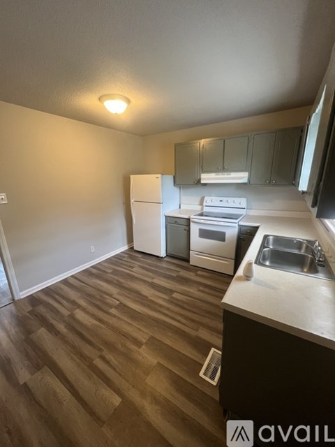 A kitchen with wooden floors and white appliances.