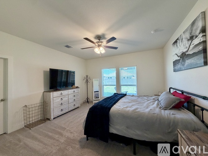 A bedroom with a bed, dresser, and ceiling fan.