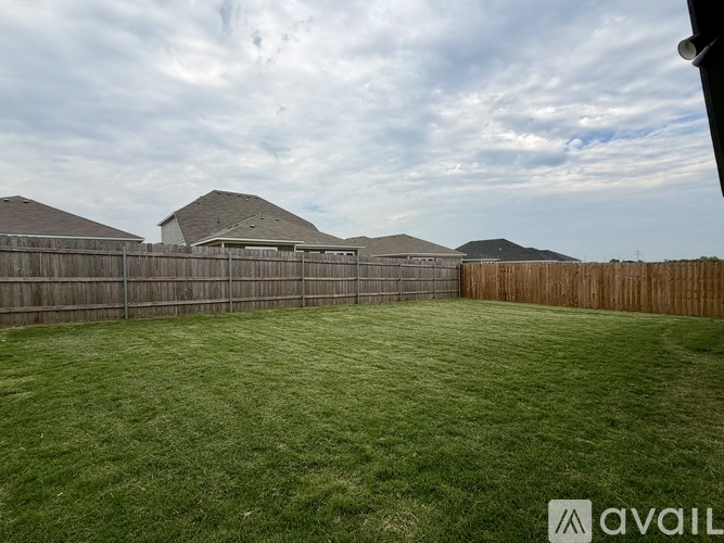 A backyard with a wooden fence and a grassy lawn.