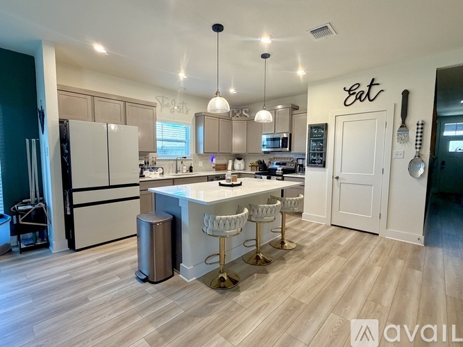 A modern kitchen with a white island and bar stools.
