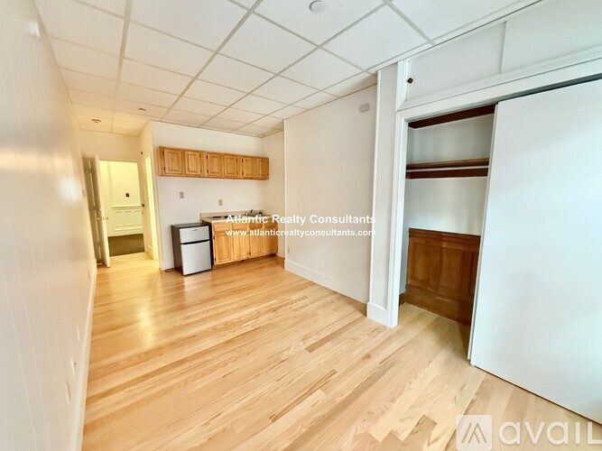 A room with wooden flooring and white walls, with a door on the right side.