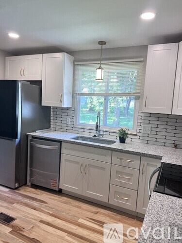 A kitchen with white cabinets and a black fridge.