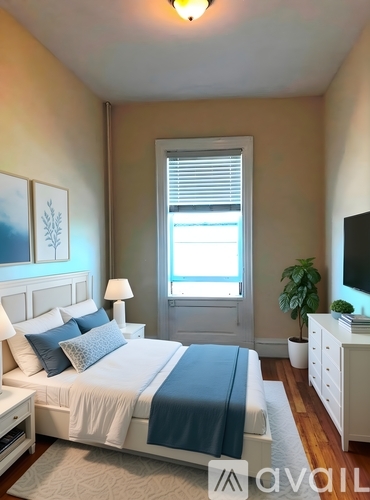 A bedroom with a bed, nightstand, and window.
