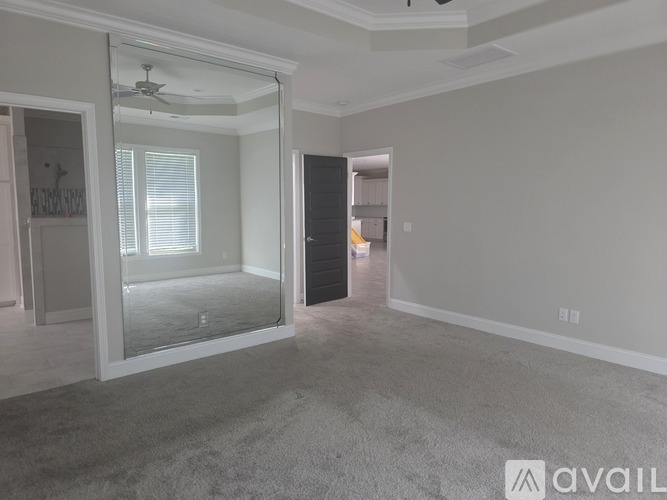 A spacious room with a carpeted floor and a sliding glass door leading to a balcony.