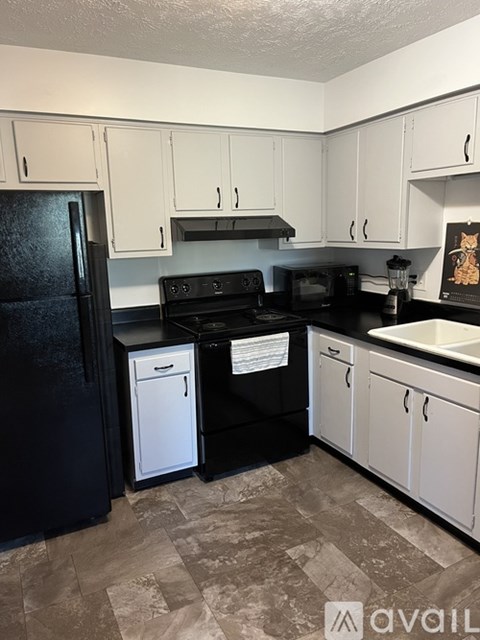 A kitchen with black appliances and white cabinets.