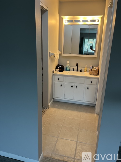 A bathroom with a white cabinet and a mirror above it.