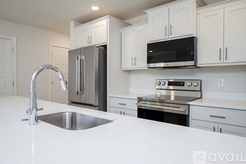 A modern kitchen with white cabinets and stainless steel appliances.