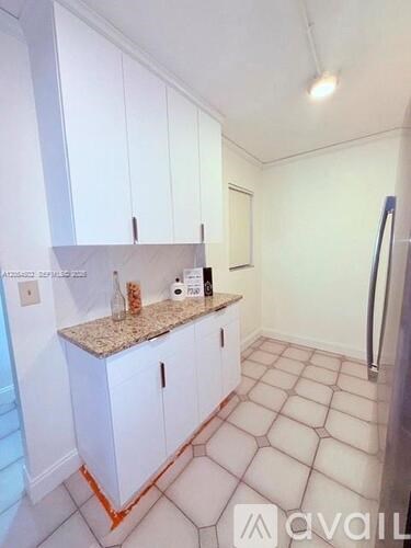 A kitchen with white cabinets and a granite countertop.