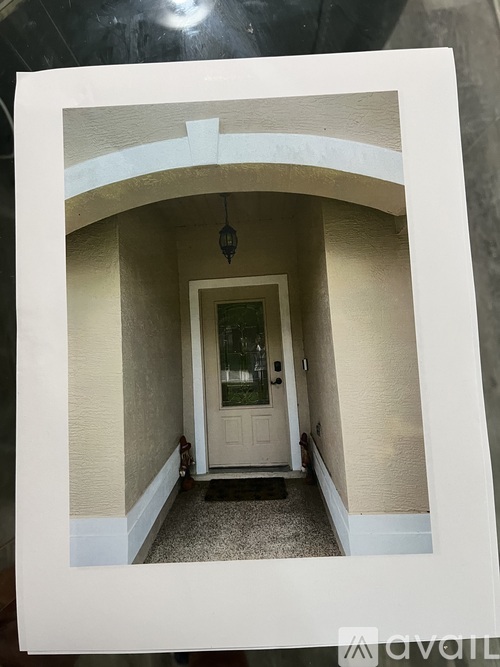 A white door is in a hallway with a light hanging from the ceiling.