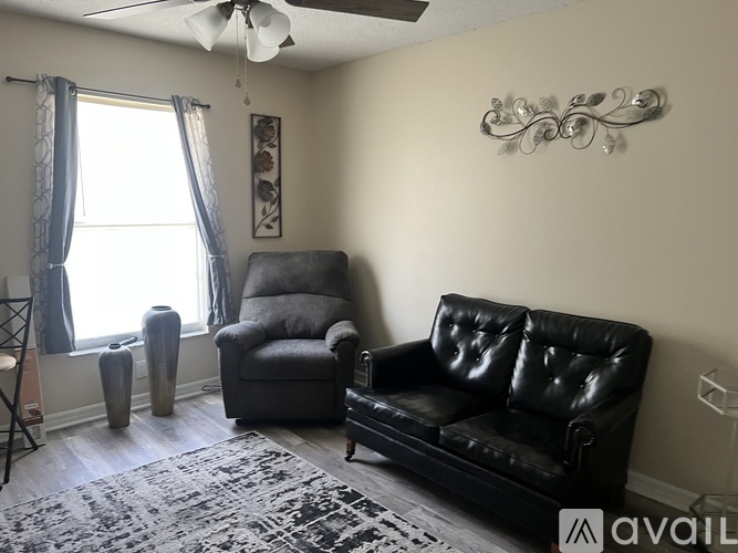 A living room with a black leather couch and a grey armchair.
