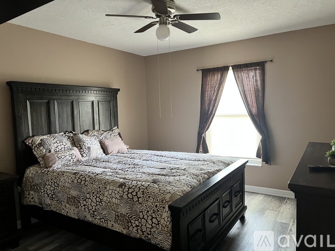 A bedroom with a large bed and a ceiling fan.
