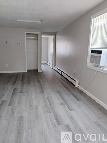 A room with a grey floor and a window with blinds.
