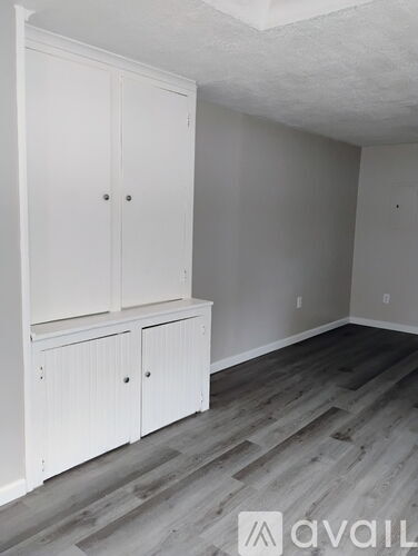 A room with white cabinets and wooden flooring.