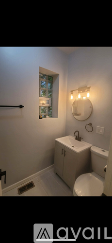 A bathroom with a toilet, sink, and mirror.