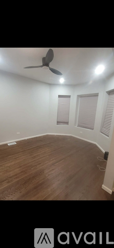 A room with a ceiling fan and wooden flooring.