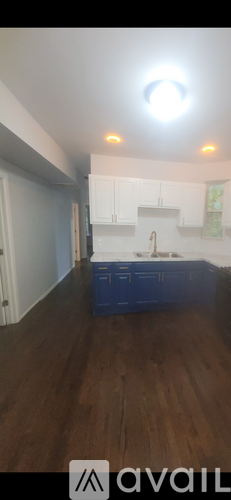 A kitchen with white cabinets and a blue container on the floor.