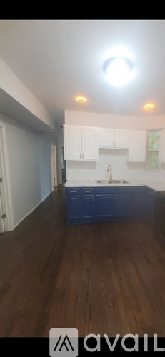 A kitchen with white cabinets and a blue container on the floor.