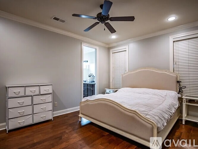 A bedroom with a bed, dresser, and ceiling fan.