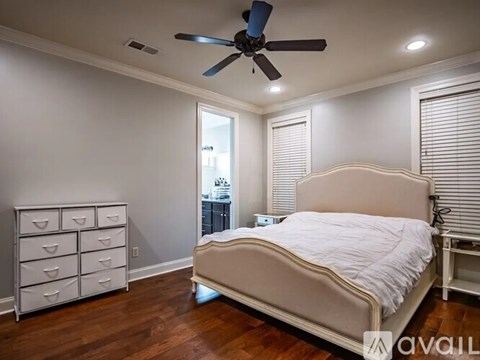 A bedroom with a bed, dresser, and ceiling fan.