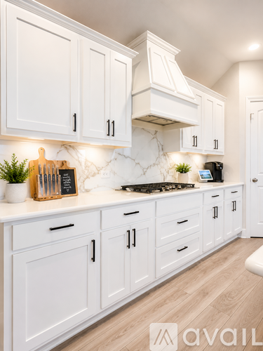 A kitchen with white cabinets and a marble backsplash.
