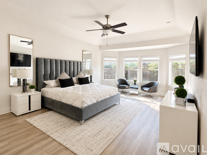 A bedroom with a large bed, a ceiling fan, and a chair.