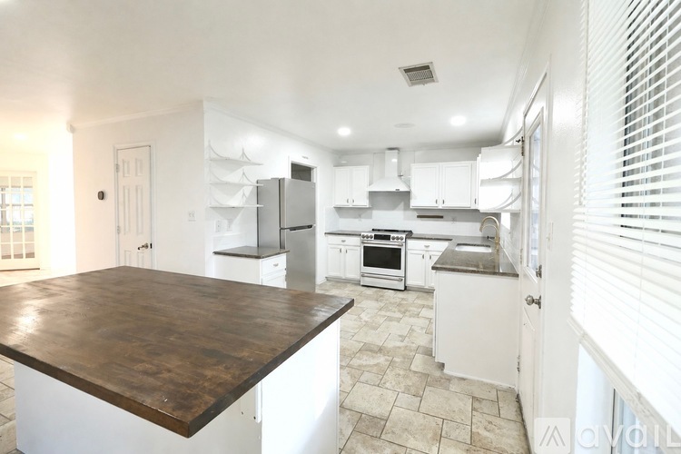 A kitchen with white cabinets and a wooden island.