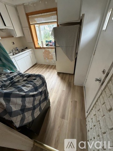 A small bedroom with a bed covered in a blue and white checkered comforter.
