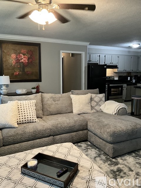 A living room with a grey couch and a painting on the wall.