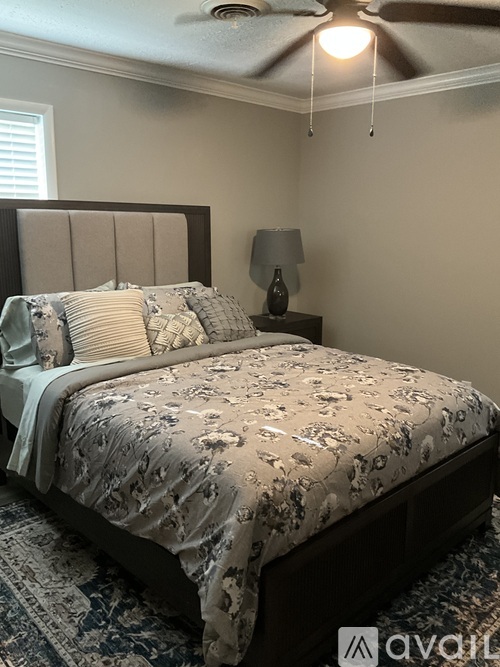 A bed with a floral patterned comforter and a lamp on a side table.