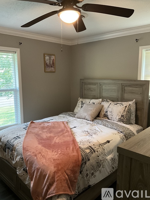 A bedroom with a large bed and a ceiling fan.
