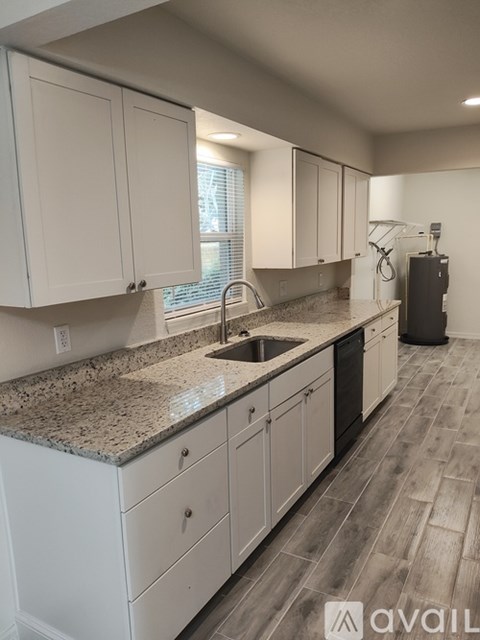 A kitchen with white cabinets and a granite countertop.