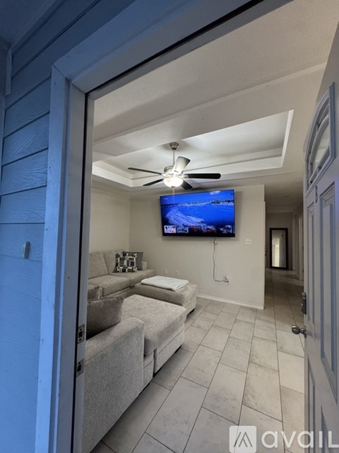 A living room with a grey couch and a flat screen TV mounted on the wall.