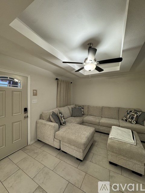 A living room with a grey couch and a ceiling fan.
